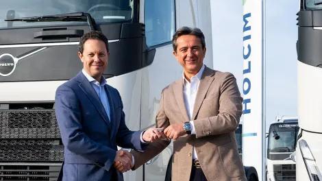 Ceo Holcim y Director general de Volvo dando la mano como señal de acuerdo  delante de camión hoclim
