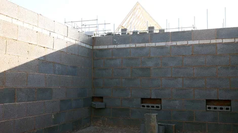 Estructura de muro de bloques en obra, destacando la base del cerramiento en contacto con el terreno, punto crítico para la capilaridad. 