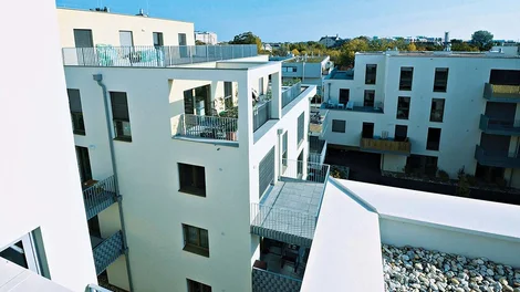 Edificio residencial moderno de fachadas claras y terrazas visto desde un ángulo superior.