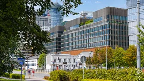 Antigua fábrica rehabilitada y transformada en zona comercial y gastronómica, con arquitectura contemporánea, zonas verdes y entorno urbano renovado como ejemplo de regeneración sostenible del parque edificado.