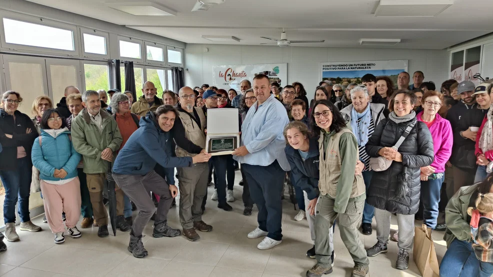 Foto grupal de los asistentes y técnicos en el interior del centro de interpretación sosteniendo una placa conmemorativa durante la jornada de puertas abiertas por el quinto aniversario del acuerdo de custodia.