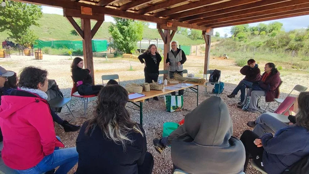 Grupo de asistentes participando en un taller de artesanía con esparto y divulgación ambiental bajo una estructura de madera en el Centro de Naturaleza La Chanta.