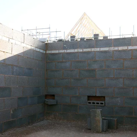 Estructura de muro de bloques en obra, destacando la base del cerramiento en contacto con el terreno, punto crítico para la capilaridad. 