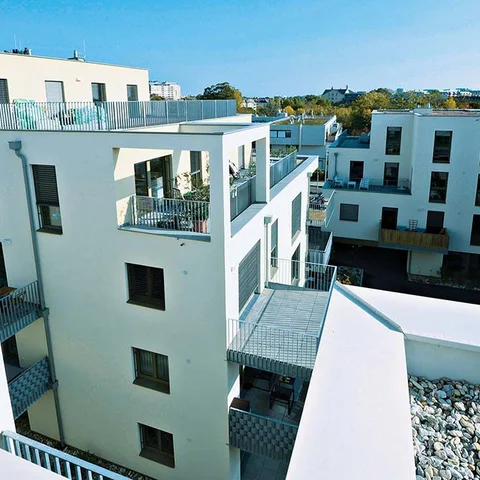 Edificio residencial moderno de fachadas claras y terrazas visto desde un ángulo superior.