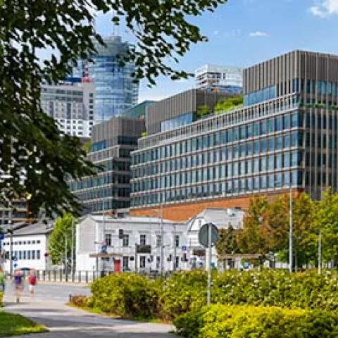 Antigua fábrica rehabilitada y transformada en zona comercial y gastronómica, con arquitectura contemporánea, zonas verdes y entorno urbano renovado como ejemplo de regeneración sostenible del parque edificado.
