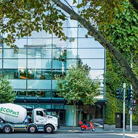 Camión hormigonera EcoPact suministrando hormigón de bajas emisiones frente a edificio urbano sostenible, ejemplo de construcción eficiente y descarbonizada.